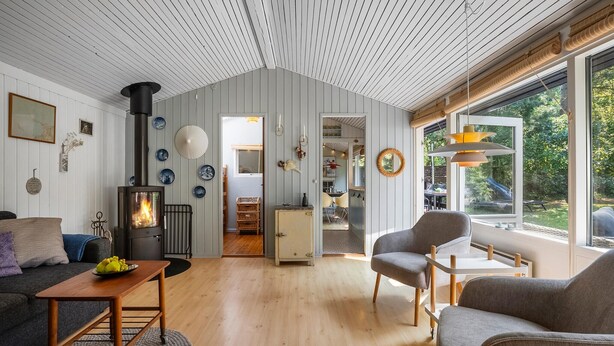Una sala de estar acogedora con chimenea, pisos de madera y vistas al exterior.