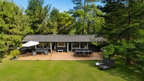 Una casa moderna con patio, mobiliario exterior y un gran paraguas.