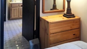 A bedroom with a wooden dresser, two bedside lamps, a mirror, and a view into the bathroom. - Pristine Condo, Walk To Lifts, 2 Fireplaces, 3 Balconies,  Mountain Views! (Vail)