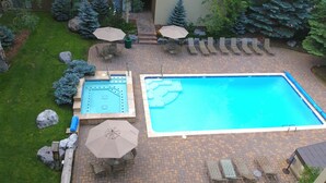 A swimming pool with a tiled deck, lounge chairs, and umbrellas. - Pristine Condo, Walk To Lifts, 2 Fireplaces, 3 Balconies,  Mountain Views! (Vail)