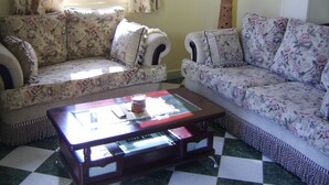 A living room with floral-patterned sofas, a glass coffee table, and a checkered floor. - A Beautiful, Family-owned Penthouse Apartment, Overlooking the Red Sea Hurghada (Qesm Hurghada)