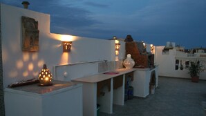 A rooftop terrace with a white wall, a stone sculpture, and a table with a vase. - A Beautiful, Family-owned Penthouse Apartment, Overlooking the Red Sea Hurghada (Qesm Hurghada)