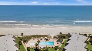 Una propiedad frente a la playa con piscina, sillas de descanso y vista al océano.