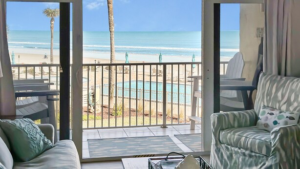 Habitación con vista a la playa y la piscina, que incluye un sofá, un sillón y una mesa de centro.