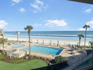 Blick auf ein Schwimmbecken mit Strand und dem Ozean im Hintergrund.