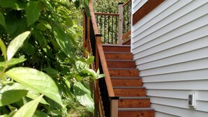 A wooden staircase leading to a white house with a metal railing.