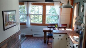 A spacious kitchen with wooden flooring, a dining table, and a built-in oven.