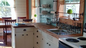 A kitchen with wooden cabinets, a stove, a sink, and a window with curtains.