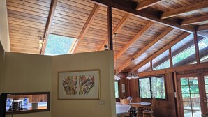 A spacious room with a high wooden ceiling, a dining area with a table and chairs, and a framed botanical print on the wall. - Hale Mauna Loa Volcano Vacation Getaway-Upper Level Volcanoes National Park  (Volcano)