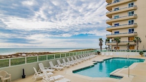 A pool area with sun loungers and a view of the ocean. - Silver Beach 103 | Updated, Direct Beach Front, Pet Friendly! (Orange Beach)