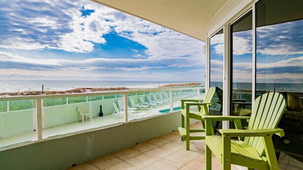 A balcony with a view of the ocean, green Adirondack chairs, and a glass railing. - Silver Beach 103 | Updated, Direct Beach Front, Pet Friendly! (Orange Beach)