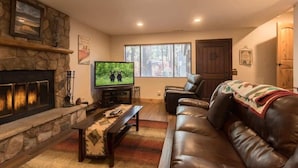 Ein Wohnzimmer mit Kamin aus Stein, Ledersofa und Fernseher.