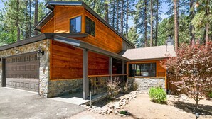 Eine moderne Blockhütte mit Steinfundament, Garage und überdachter Veranda.