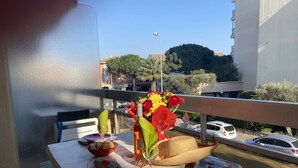 A balcony table set with plates, a wine bottle, a bowl, a knife, a fork, and a magazine. - Cozy Studio Near Beach & Shops - Sleeps 2 (Fréjus)