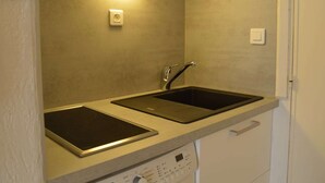 A compact kitchen with two sinks, a built-in oven, and a dishwasher. - Cozy Studio Near Beach & Shops - Sleeps 2 (Fréjus)