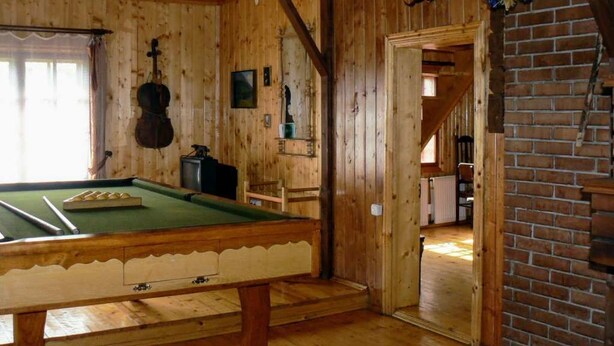 Une pièce en bois avec une table de billard, un escalier et un mur en briques.