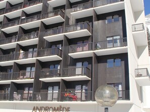 Un hôtel à plusieurs étages doté d’une architecture moderne, avec des balcons pourvus de garde-corps en métal et offrant une vue dégagée sur les environs.