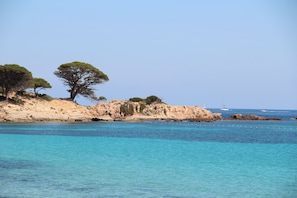 Un paisaje costero con aguas turquesas cristalinas, acantilados rocosos y vegetación escasa.