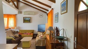 A cozy living room with a sofa, a television, and a wooden cabinet. - PORTO-VECCHIO - 5 MIN FROM PALOMBAGGIA BEACHES<br> (Porto-Vecchio)