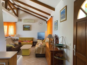 A cozy living room with a sofa, a television, and a wooden cabinet.