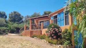 Ein Haus mit einer Veranda, einem gepflasterten Weg und umgebender Bepflanzung.