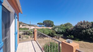 A balcony with a view of a hillside, a clear sky, and some vegetation. - PORTO-VECCHIO - 5 MIN FROM PALOMBAGGIA BEACHES<br> (Porto-Vecchio)
