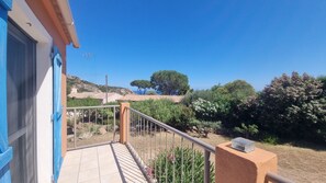 Ein Balkon mit Blick auf eine Hügellandschaft, einen klaren Himmel und etwas Vegetation.