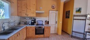 Cuina amb armaris de fusta, forn integrat, cafetera i finestra.