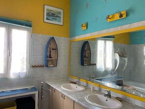 A bathroom with two sinks, a large mirror, and a window with curtains.