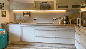 Een moderne keuken met een centraal eiland, inbouwapparatuur en een roestvrijstalen spoelbak.