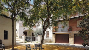 A courtyard with a tree, two benches, and a building with a balcony. - Blau Masnou (El Masnou)