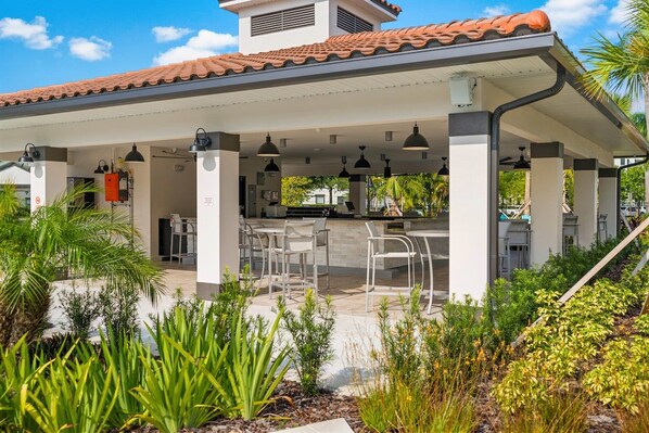 An outdoor covered patio area with seating and a kitchen area.