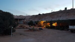 Un paysage désertique avec un bâtiment doté d’un patio couvert.