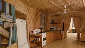 Une cuisine compacte équipée d’un réfrigérateur, d’un four à micro-ondes, d’une cuisinière et de meubles de rangement en bois.