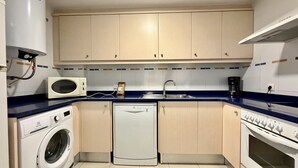 A compact kitchen with a washing machine, microwave, dishwasher, and a coffee maker.