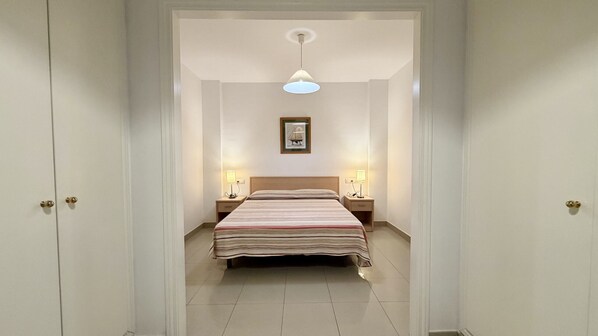 A hotel room with a bed, two bedside lamps, a framed picture on the wall, and a ceiling light.