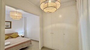 A bedroom with a bed, bedside table, lamp, and a wardrobe with two doors.