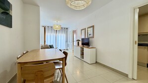 A modern living room with a dining area, a TV, and a bookshelf.