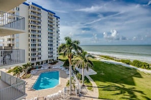 Un hôtel de grande hauteur doté d’une piscine, offrant une vue sur la plage et comprenant plusieurs balcons.
