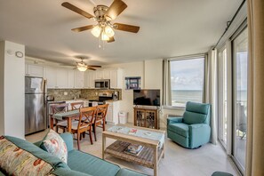 Enjoy ocean views from the large window in this inviting living space, featuring a sofa, dining area, and recliner.