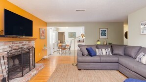 Ein Wohnzimmer mit Kamin, grauem Sofa und Flachbildfernseher.