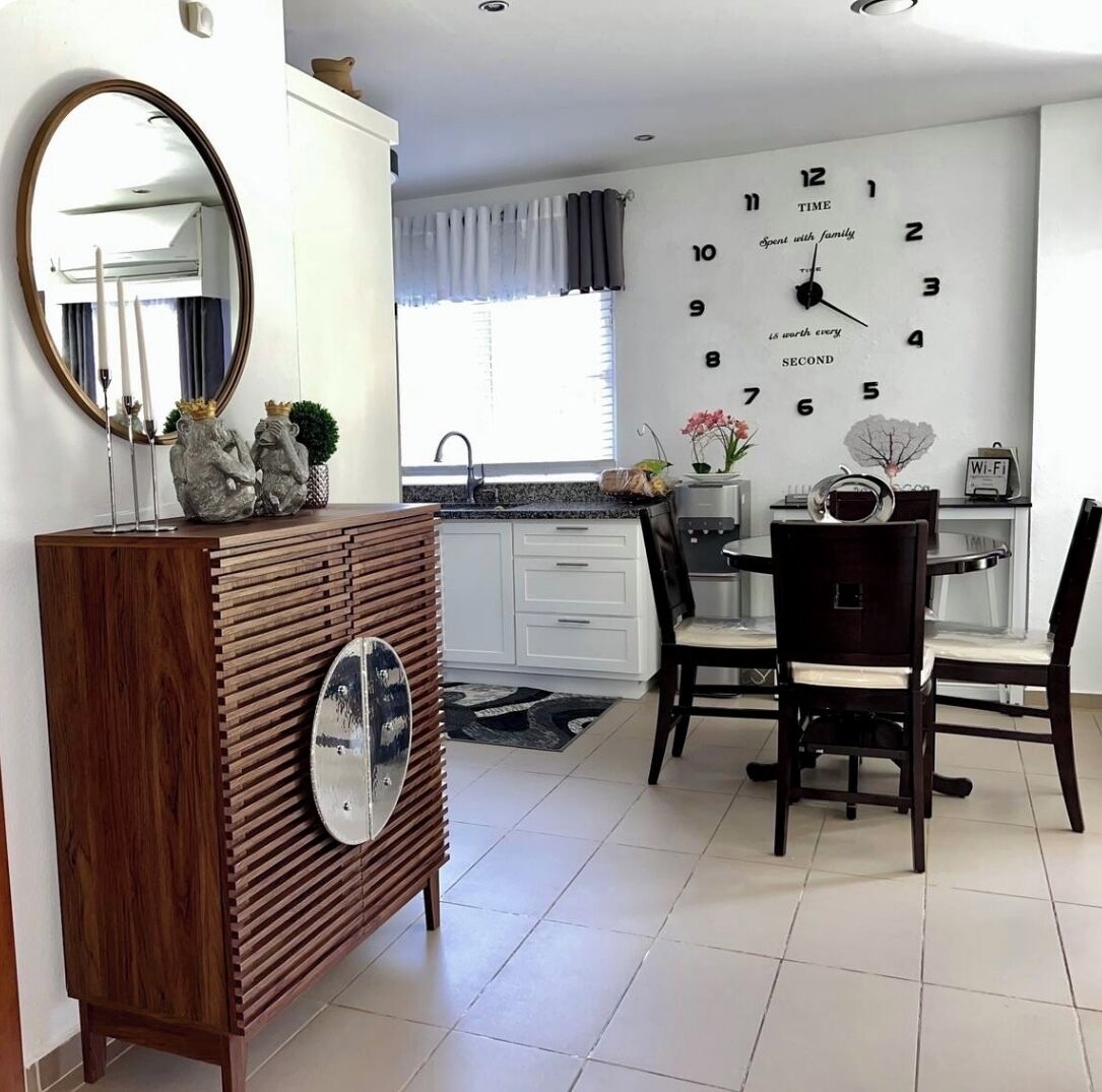 Une cuisine moderne avec une horloge, une table à manger, des chaises et un miroir.