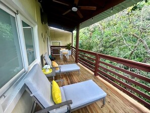 A wooden deck with two lounge chairs and a table, overlooking a lush green landscape. - SunnyHills House, Roatan, Honduras (Coxen Hole,)