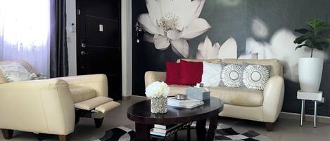 Ein modernes Wohnzimmer mit zwei Sofas, einem Couchtisch und einem großen floralen Wandbild.