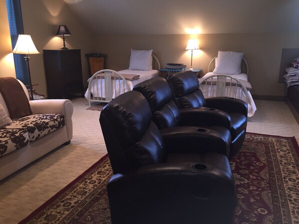A living room with a leather sofa, a patterned armchair, a small table, and a crib.