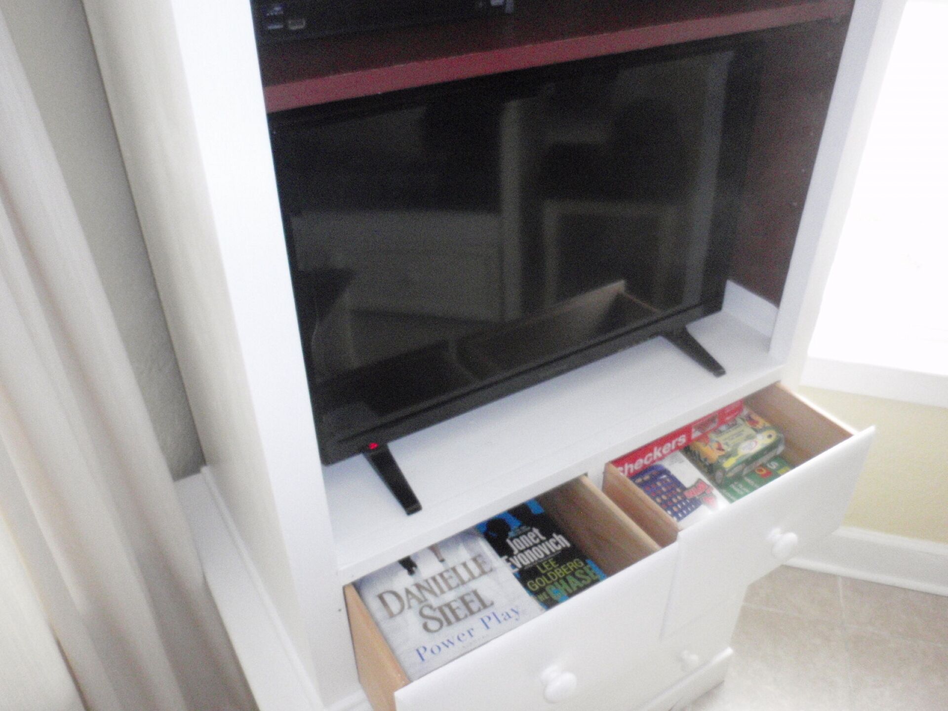 Eine weiße Unterhaltungseinrichtung mit Fernseher und einer Schublade für Bücher.