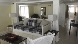 Un dormitorio con cama, mesitas de noche, una silla, escritorio y espejo.