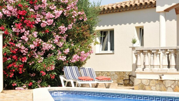A swimming pool with lounge chairs and a stone wall.