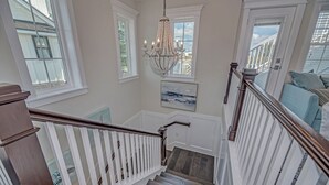 Una escalera con barandillas blancas, escalones de madera y un candelabro.