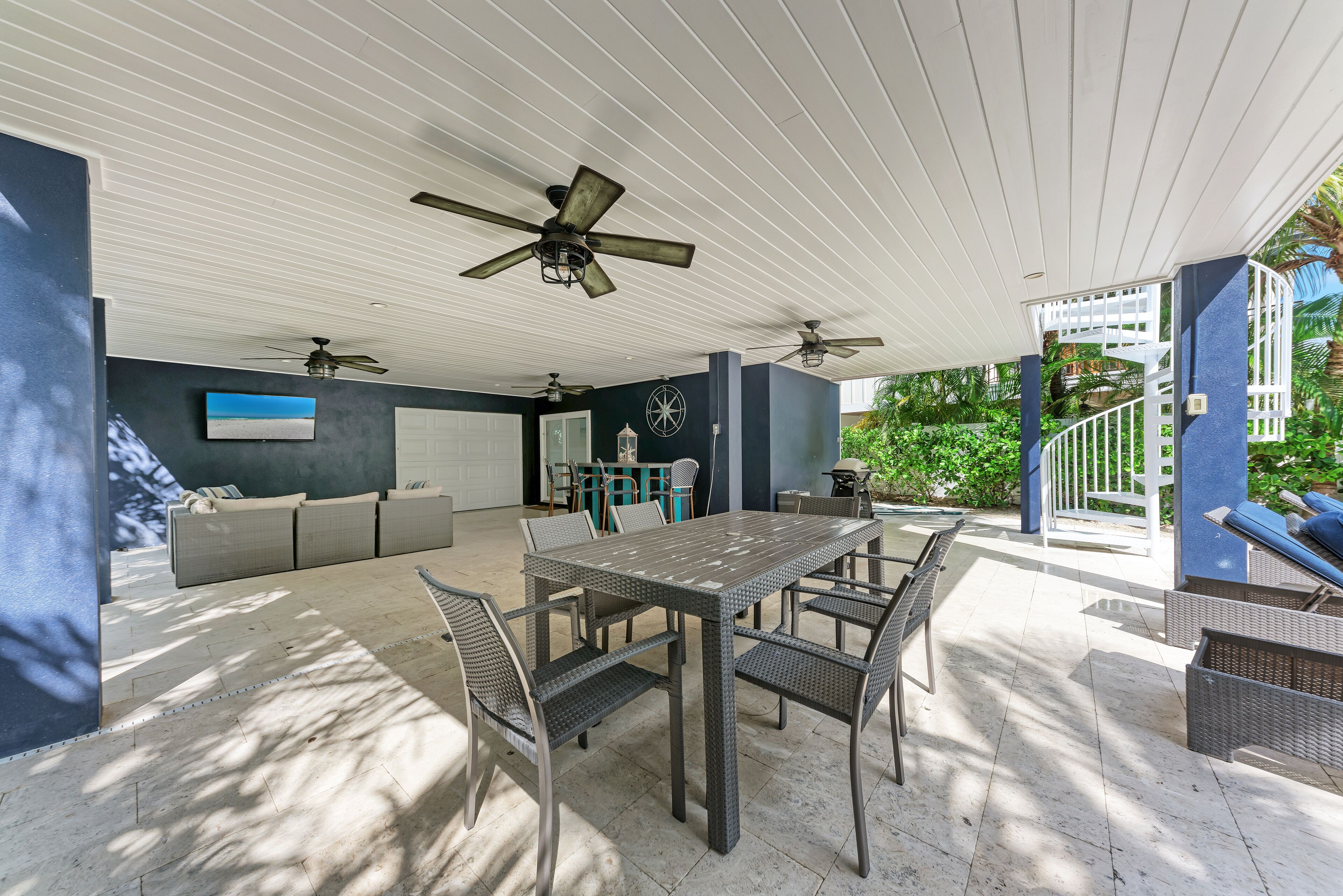 An outdoor patio with a dining table, chairs, and ceiling fans.